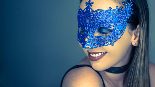 Smiling woman wearing mask against gray background