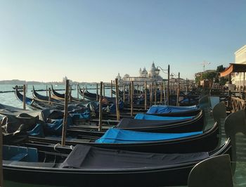 Boats moored in canal against clear blue sky