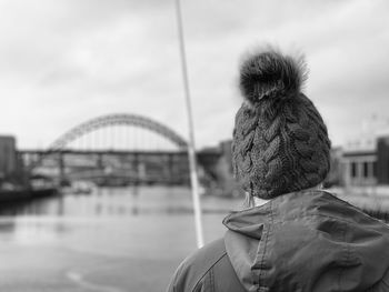 Rear view of woman wearing a knit hat standing on a bridge
