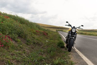 Bicycle on road amidst field against sky