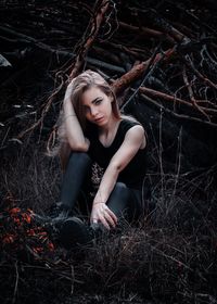 Portrait of beautiful young woman sitting on land