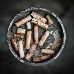 High angle view of cigarette butts in rusty ashtray