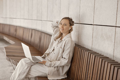 Portrait of woman using laptop while sitting on bench