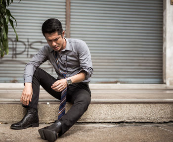 Businessman sitting on footpath