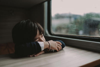 Boy relaxing on table by window in train