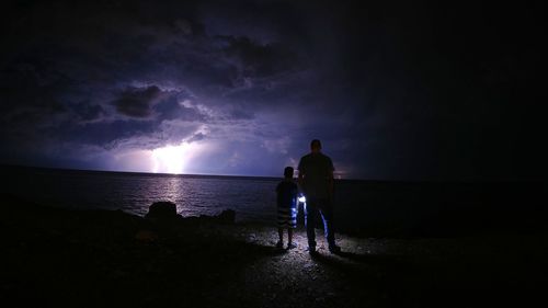 Rear view of silhouette people on beach against sky