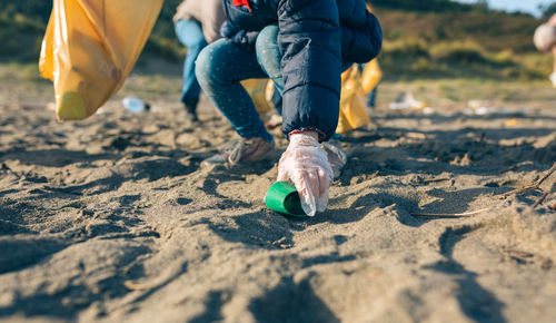 Low section of girl picking garbage at beach