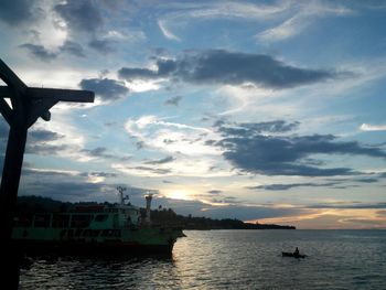 Boats in sea against cloudy sky at sunset