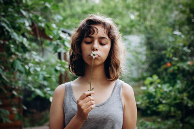 Portrait of young woman standing against plants