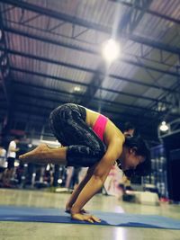 Side view of female athlete in yoga pose at health club