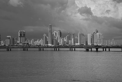 Sea by buildings against sky in city