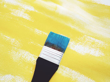 High angle view of paintbrush on yellow fabric