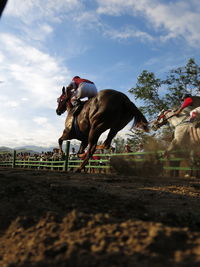 Men horseback riding in race against sky