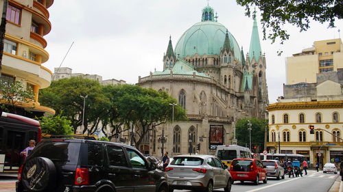 Vehicles on road amidst buildings against sky in city