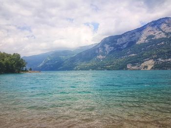 Scenic view of sea by mountains against sky