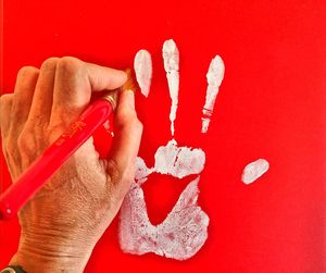 Close-up of hand holding paintbrush for cleaning handprint on wall