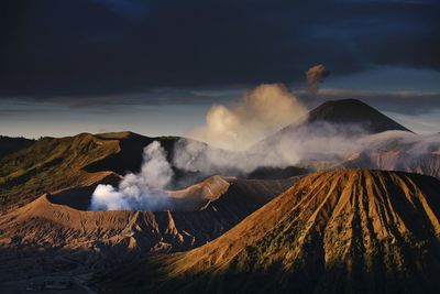 Smoke emitting from volcanic mountains against sky