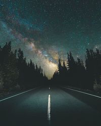 Road amidst trees against sky at night