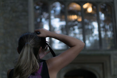 Rear view of woman photographing through camera in historic building