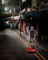 Rear view of man on illuminated street at night