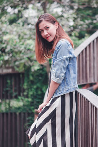 Portrait of woman standing against railing