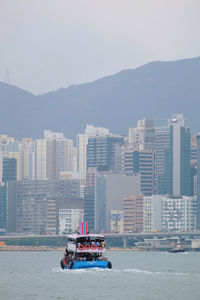 Boats in sea against buildings in city