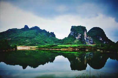 Mountains by lake against cloudy sky