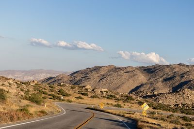 Road leading towards mountains against sky