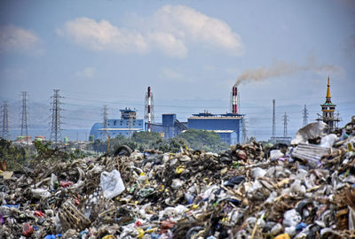 Stack of garbage by sea against sky