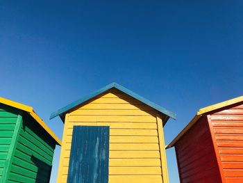 Low angle view of colourful beach huts against blue sky