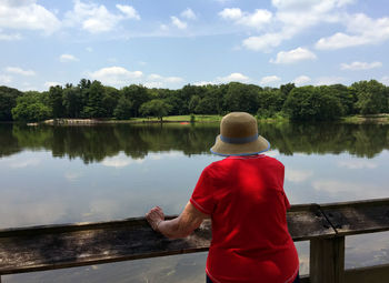 Rear view of woman standing by lake against sky