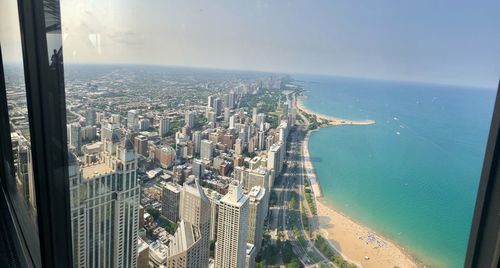 High angle view of modern buildings by sea against sky