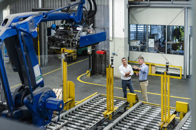 Male supervisor discussing with coworker about machinery in factory