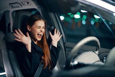 Young woman screaming sitting in car at night