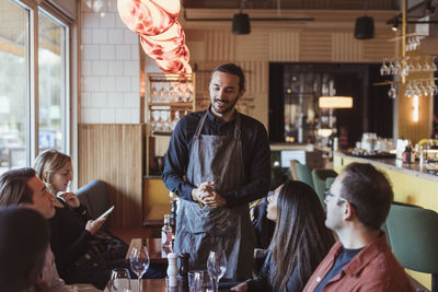 Multiracial customers ordering food from waiter in restaurant