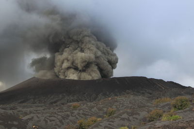 Smoke emitting from volcanic mountain against sky