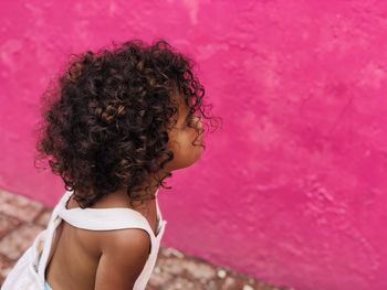 Side view of girl looking at pink wall