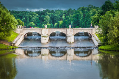 Arch bridge over river against trees