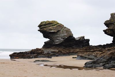 Rock formation on beach against sky