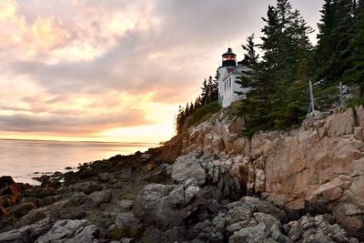 Rock formations by sea against sky during sunset