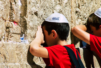Rear view of man looking at camera against wall