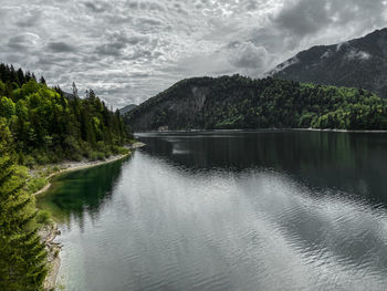 Scenic view of lake sylvensteinstausee on stormy weather against sky and mountains
