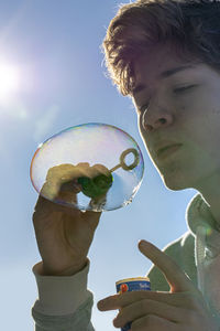 Portrait of boy holding a bubble against sky