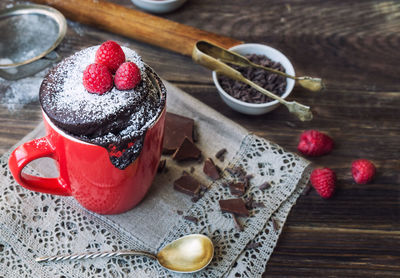 Fresh homemade chocolate cake in mug on rustic wooden background. cooked in microwave.