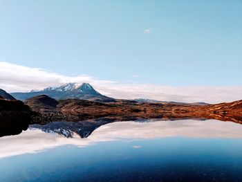 Scenic view of lake by snowcapped mountains against sky