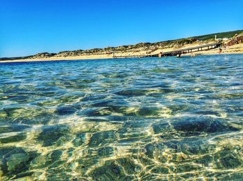 Scenic view of beach against clear blue sky