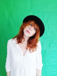 Portrait of beautiful young woman standing against green background