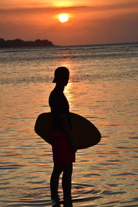 Silhouette man standing on beach during sunset