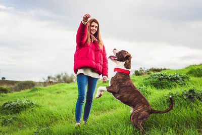 Full length of woman with dog on field