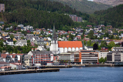 Houses by river against buildings in city